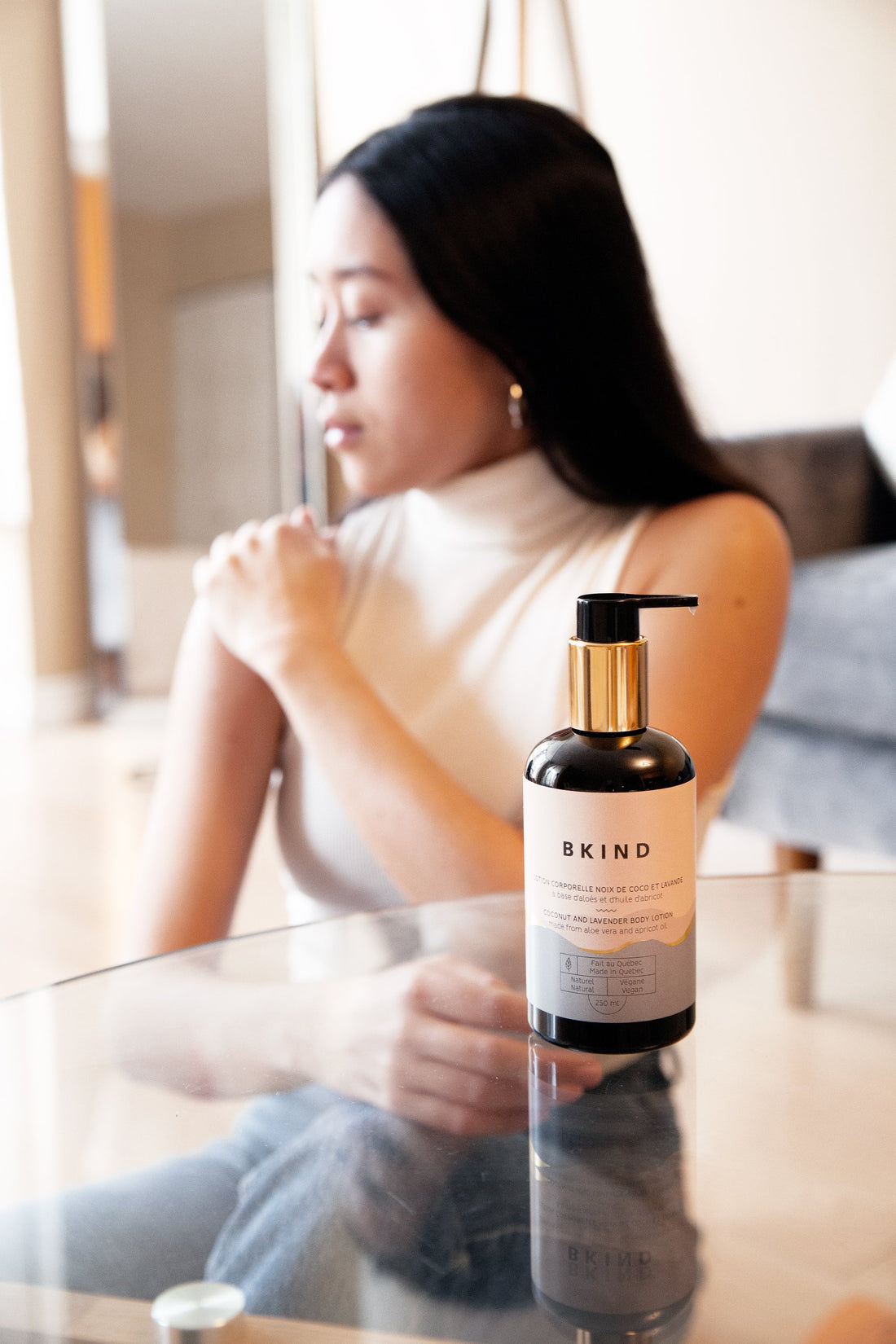 A woman applies body lotion to her shoulder 