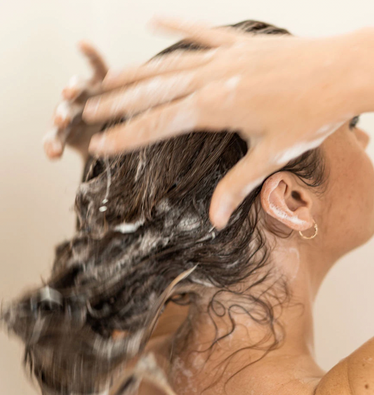 A person washing their long hair in a shower 