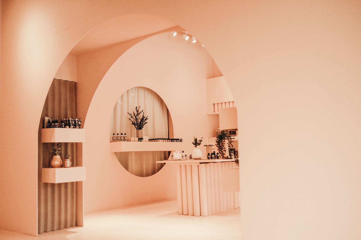 Interior of the retail store. The walls are a soft peach color and products are neatly stacked on shelves. 