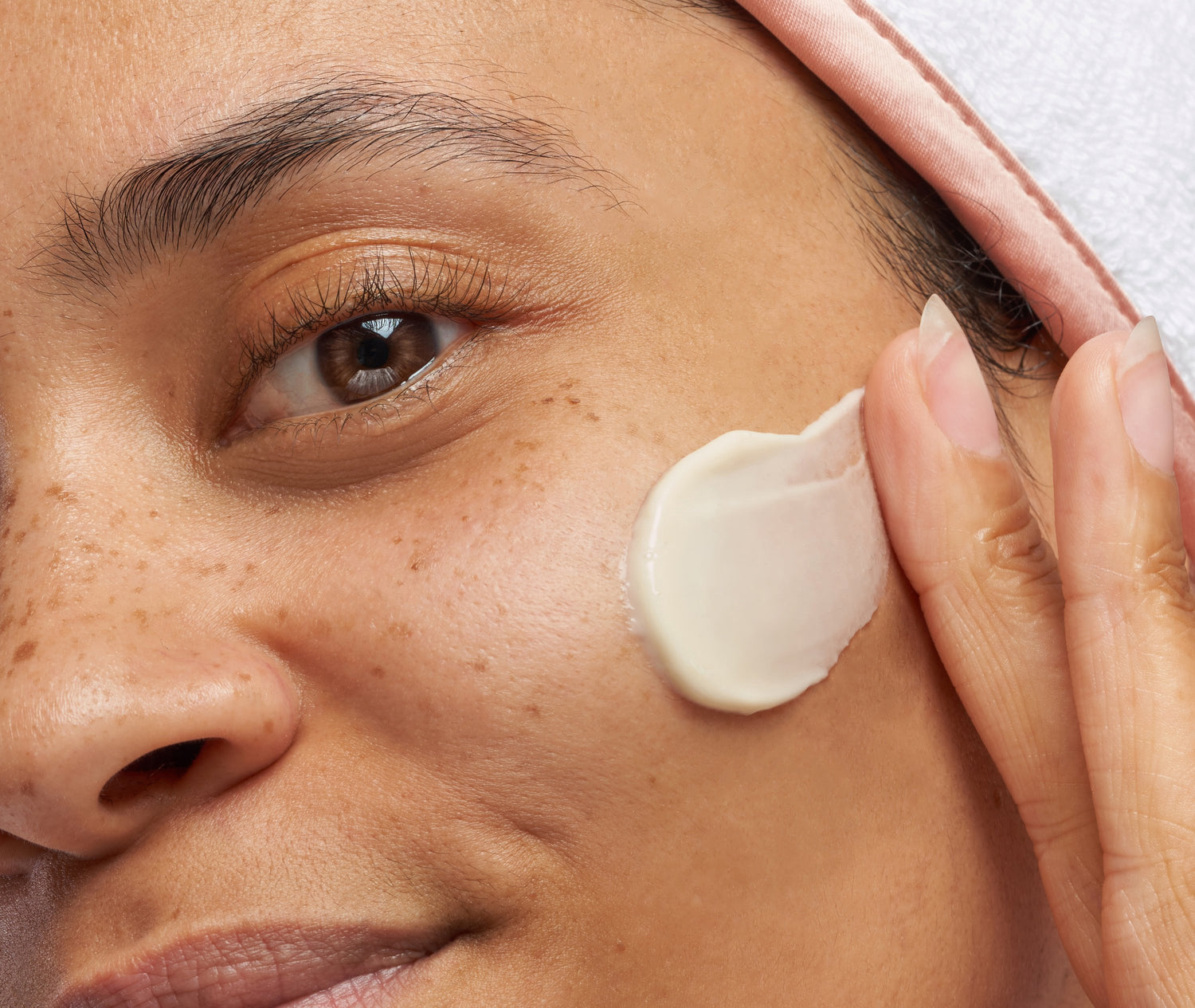 Woman applying cream on her cheek using her fingertips